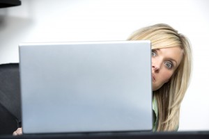 Hiding Behind Laptop at Office Desk | Shutterstock.com