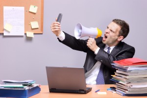 Man Yelling into Phone at Office | Shutterstock.com